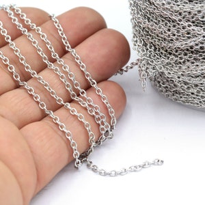 Puede incluir: Una cadena plateada, mostrada en primer plano, está enrollada en un carrete y dispuesta en línea recta sobre una mano. La cadena está hecha de pequeños óvalos unidos.