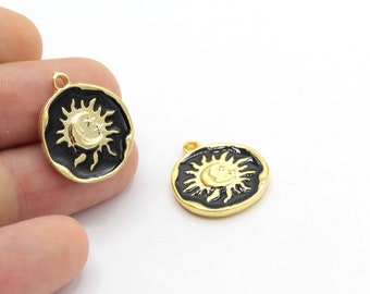 Könnte beinhalten: Goldfarbene runde Anhänger mit schwarzem Emaille-Rand. Jeder Anhänger zeigt ein goldenes Sonne-und-Mond-Design. Die Anhänger haben oben eine kleine Schlaufe zum Befestigen an einer Kette oder anderem Schmuck.