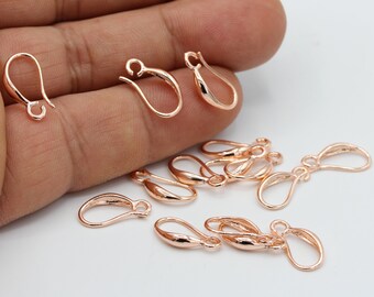 May include: A close-up of rose gold earring hooks. The hooks are made of metal and have a smooth finish. They are perfect for making earrings.