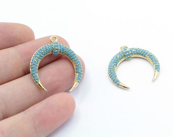 Puede incluir: Dos abalorios de media luna dorados con detalles de cristal azul. Los abalorios tienen una punta puntiaguda y un bucle en la parte superior para sujetarlos a joyas.