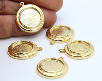 Puede incluir: Cinco bandejas redondas de metal dorado para colgantes, con un borde elevado y un pequeño bucle en la parte superior. Las bandejas son perfectas para agregar un toque personal a la elaboración de joyas.