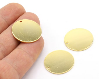May include: Three gold-colored metal circles with a small hole in the center. The circles are smooth and shiny.