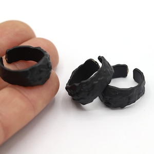 Könnte beinhalten: Drei schwarze Ringe aus strukturiertem Metall. Die Ringe sind offen und haben eine raue, unebene Oberfläche.
