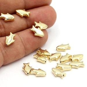 Peut inclure: Un groupe de perles en forme de poisson de couleur dorée. Les perles sont petites et ont une finition lisse et brillante.