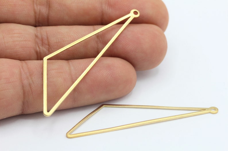 May include: Two gold-colored metal triangle shapes with a small loop at the top. The triangles are open and have a flat, smooth surface.