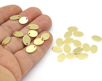 May include: A collection of gold oval-shaped metal charms with a hole at the top. The charms are scattered on a white surface.