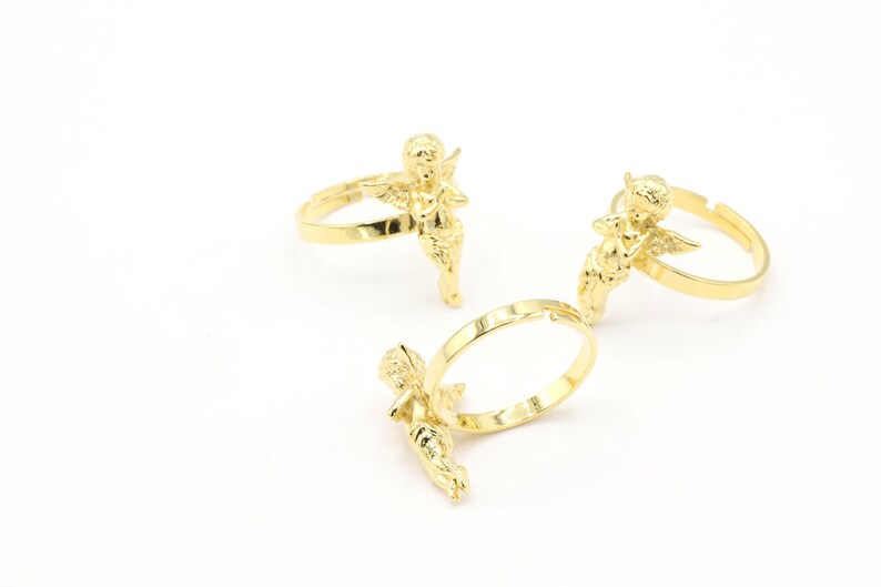 May include: Three gold-tone rings with angel figurines. Each ring features a detailed angel design with wings and a flowing gown.