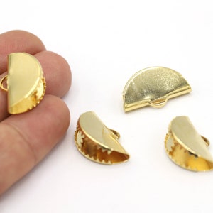 May include: Four gold-colored metal half-circle clasps with a decorative edge. The clasps have a small loop on the top.