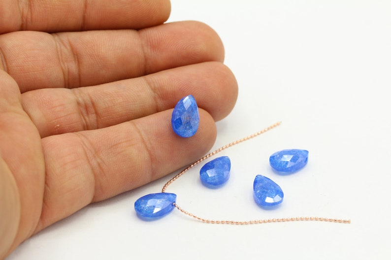 Pu&ograve; includere: Un filo di catena in oro rosa con cinque perle di pietra preziosa blu a forma di goccia.