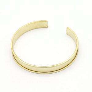 May include: A gold-toned metal bangle bracelet with a smooth, polished finish.