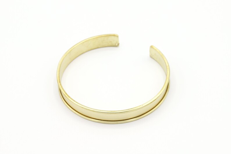 May include: A gold-toned metal bangle bracelet with a smooth, polished finish.