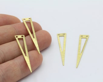 May include: Four gold triangle shaped metal charms with two holes at the top. The charms are on a white surface.