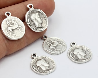 May include: Five silver-toned metal charms in the shape of ancient Greek coins. Each charm features a different design, including a horse, a woman's profile, and a mythical creature.