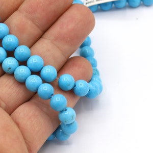 May include: A strand of turquoise blue round beads, approximately 6mm in diameter, strung on a clear elastic cord.