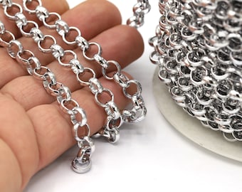 May include: A silver chain with round links, shown in a close-up view. The chain is coiled on a spool and also laid out straight on a hand.