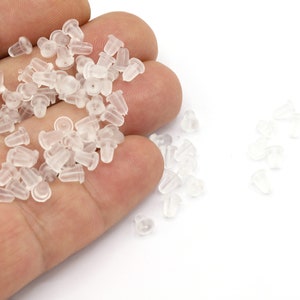 Peut inclure: Un tas de dos d'oreille en plastique transparent. Les dos sont petits et ronds, avec un petit trou au centre. Ils sont conçus pour être utilisés avec des boucles d'oreilles à clous.