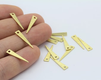 May include: A group of 12 gold-toned metal triangle charms with a hole at the top. The charms are scattered on a white surface.