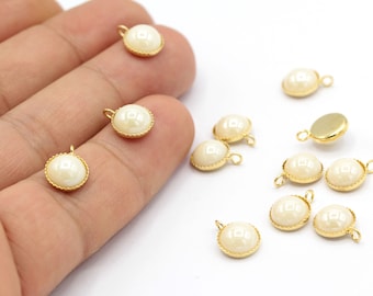 May include: A collection of 12 gold-toned metal charms with white pearl-like cabochons. Each charm has a loop for attaching to jewelry or other crafts.