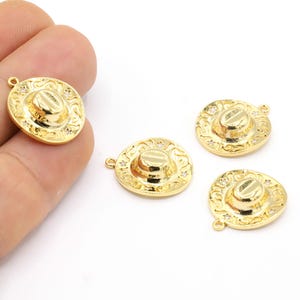 Puede incluir: Cuatro abalorios de metal dorado en forma de sombreros de vaquero con pequeños diamantes de imitación transparentes alrededor del borde.