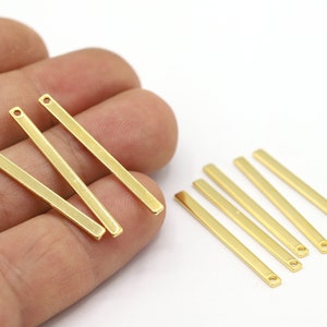 May include: A set of ten gold-coloured metal bars with a hole at each end. The bars are approximately 2.5 cm long.