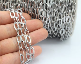 May include: A silver chain with oval links. The chain is coiled and held in a hand.