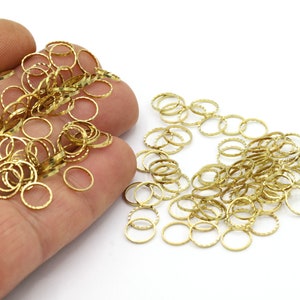 May include: A large pile of gold-colored jump rings. The rings are small and have a textured surface.