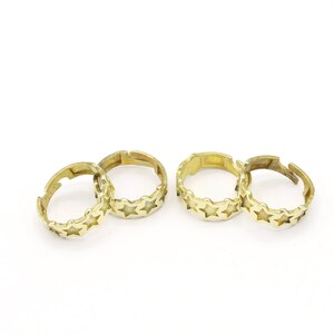 May include: Four gold-toned rings with a star design. The rings are open and can be adjusted to fit different finger sizes.