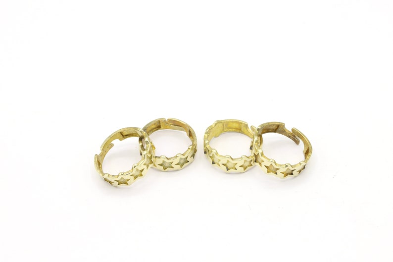 May include: Four gold-toned rings with a star design. The rings are open and can be adjusted to fit different finger sizes.