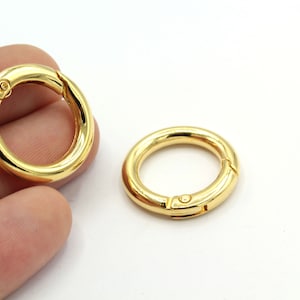 Può includere: Due portachiavi in metallo dorato con chiusura a molla. Gli anelli sono rotondi e hanno una finitura liscia.
