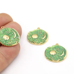 以下が含まれることがあります： 緑色のエナメル仕上げのゴールドトーンチャーム3個。各チャームは、隆起した中心と側面に三日月形を持つ円形のデザインが特徴です。チャームは、ジュエリープロジェクトに遊び心を加えるのに最適です。