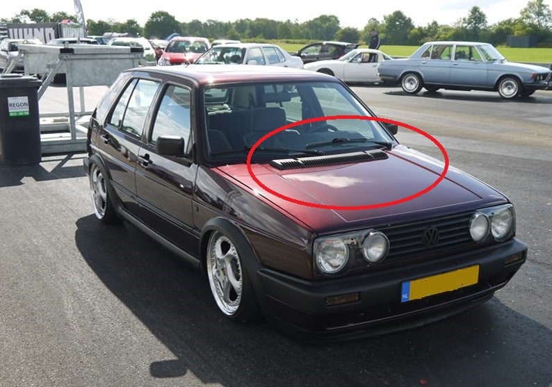 May include: A maroon Volkswagen Golf with a black grille and a black bumper. The car has a black windshield wiper and a black air intake on the hood.