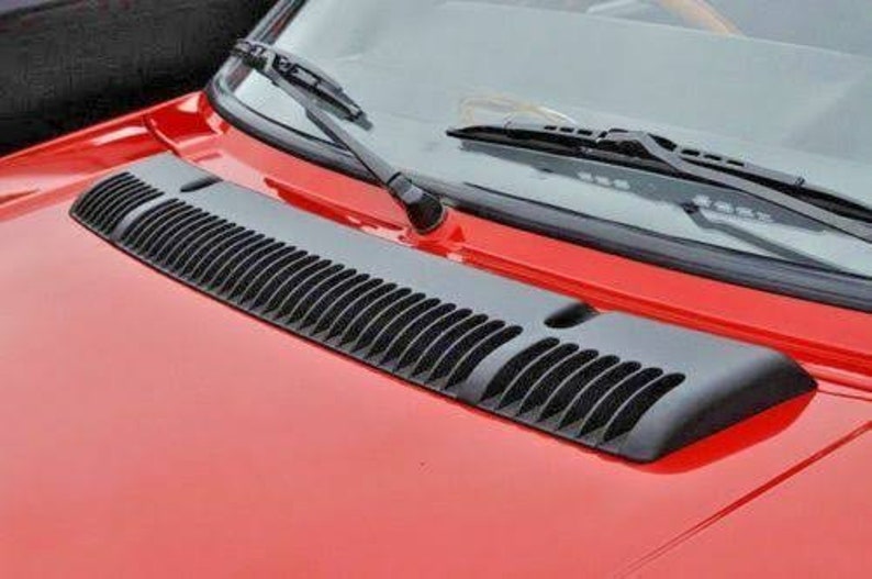 May include: A red car with a black plastic air vent on the hood.