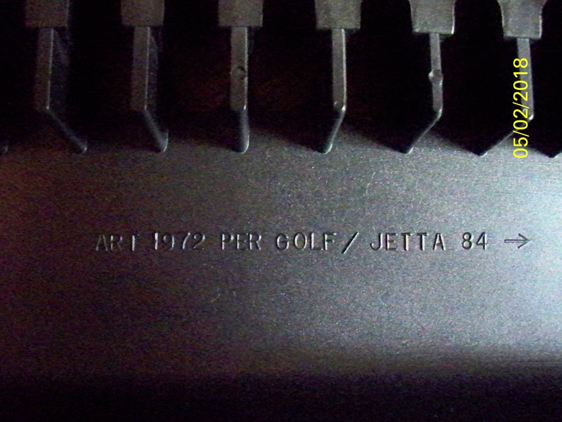 May include: Close-up of a black plastic part with the text "ART 1972 PER GOLF / JETTA 84 ->" printed on it.