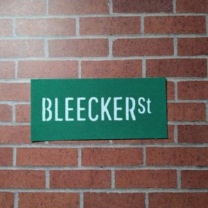 Puede incluir: Un letrero de calle verde con letras blancas que dice "BLEECKER St."