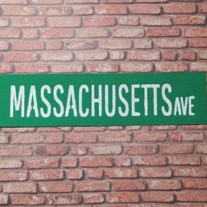 May include: A green street sign with white lettering that reads "MASSACHUSETTS AVE".
