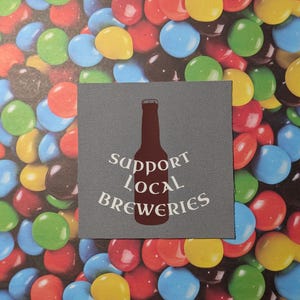 May include: A gray fabric patch with a white silhouette of a beer bottle and the text "Support Local Breweries".