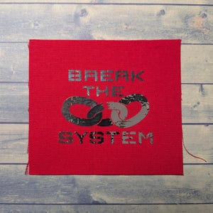 May include: Red fabric patch with silver foil lettering that reads "BREAK THE SYSTEM" with a silver foil chain link design.
