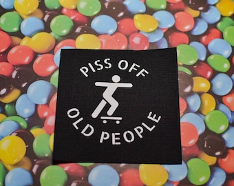 May include: Black patch with white text that reads "Piss Off Old People" with a stick figure skateboarding in the center.