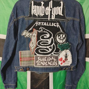 May include: A blue denim jacket with various band patches sewn on the back, including Lamb of God, Metallica, Slayer, and Suicidal Tendencies.