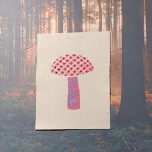 Peut inclure: Un champignon rose et violet brodé sur un patch en toile blanche. Le champignon a un chapeau à motifs et une tige texturée.