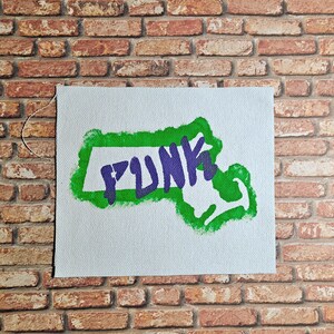 May include: A white canvas patch with a green outline of the state of Massachusetts. The word "PUNK" is written in purple inside the outline.