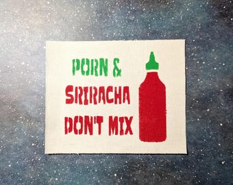 May include: A white canvas patch with the text "Porn & Sriracha Don't Mix" in green and red lettering. A red and green sriracha bottle is pictured to the right of the text.