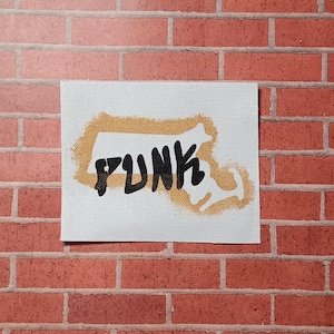 May include: A white canvas patch with a brown outline of the state of Massachusetts and the word "PUNK" written in black inside the outline.