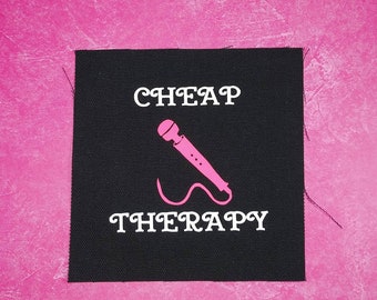 May include: Black fabric patch with white text that reads "CHEAP THERAPY" and a pink microphone graphic.