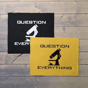 May include: Two fabric patches with the text "QUESTION EVERYTHING" and a microscope graphic. One patch is black with white text and graphic, the other is yellow with black text and graphic.