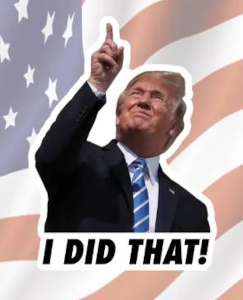 Może przedstawiać: Naklejka z fotografią mężczyzny w garniturze, z uniesioną ręką wskazującą w g&oacute;rę. Tło to rozmyte zdjęcie amerykańskiej flagi. Tekst "I DID THAT!" jest wydrukowany czarnymi literami na białym tle pod zdjęciem.