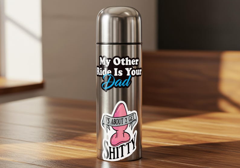 Pode incluir: Uma garrafa de &aacute;gua isolada em a&ccedil;o inoxid&aacute;vel com tr&ecirc;s adesivos. O adesivo superior diz "My Other Ride Is Your Dad" em texto preto e branco com um "Dad" azul. O adesivo do meio &eacute; um plug anal rosa com o texto "IT'S ABOUT 2 GET".
