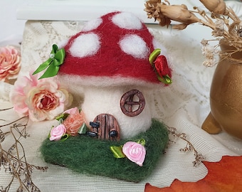 May include: A felt mushroom house with a red and white top, a white base, a small brown door, and a brown window. The house is surrounded by green felt grass and pink felt flowers.