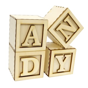May include: Wooden alphabet blocks spelling out the word "ANDY" in all caps. The blocks are light brown and have a natural wood finish.