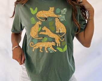 May include: A green t-shirt with a print of five leopards and tropical leaves. The leopards are in various poses, including lying down, sitting, and walking.